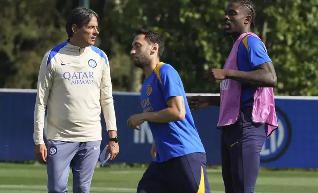 Inter Milan's head coach Simone Inzaghi watches Hakan Calhanoglu, center, and his teammate Marcus Thuram during a training session of the Champions League Media Day in view of the Saturday's Champions League final against PSG, at the Inter Milan training center, in Appiano Gentile, Italy, Monday, May 26, 2025. (AP Photo/Antonio Calanni)