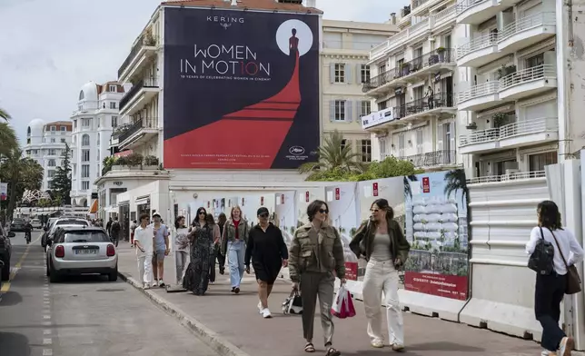 People walk along the Boulevard de la Croisette ahead of the 78th international film festival in Cannes, southern France, Sunday, May 11, 2025. The Cannes film festival runs from May 13 until May 24, 2025. (AP Photo/Lewis Joly)