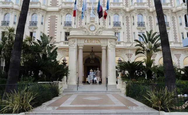 People enter the Carlton Hotel along the Boulevard de la Croisette ahead of the 78th international film festival in Cannes, southern France, Sunday, May 11, 2025. The Cannes film festival runs from May 13 until May 24, 2025. (AP Photo/Lewis Joly)