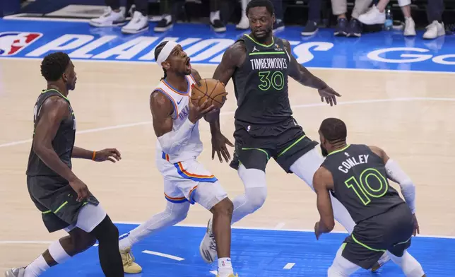 Oklahoma City Thunder guard Shai Gilgeous-Alexander, center, drives to the basket against Minnesota Timberwolves guard Anthony Edwards, left, forward Julius Randle (30) and guard Mike Conley (10) during the first half of Game 1 of an NBA basketball Western Conference Finals playoff series Tuesday, May 20, 2025, in Oklahoma City. (AP Photo/Nate Billings)