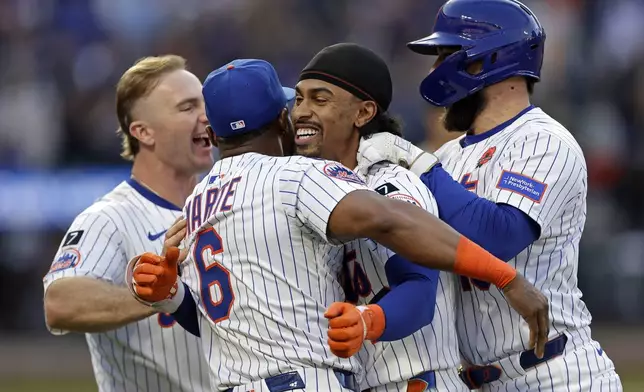 New York Mets' Francisco Lindor, second from right, is congratulated by teammates after hitting a walkoff sacrifice fly during the ninth inning of a baseball game against the Chicago White Sox, Monday, May 26, 2025, in New York. (AP Photo/Adam Hunger)