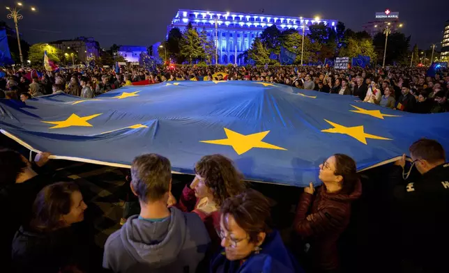 People wave a European Union flag during a pro-EU rally ahead of the second round of the presidential election redo in Bucharest, Romania, Friday, May 9, 2025. (AP Photo/Andreea Alexandru)