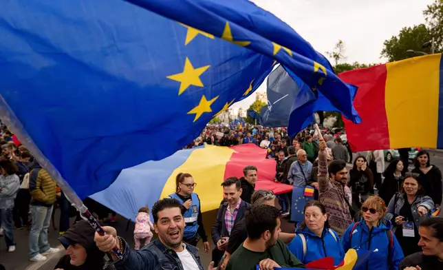 A man waves an EU flag next to a large Romanian flag during a Pro-EU rally ahead of the second round of the presidential election redo in Bucharest, Romania, Friday, May 9, 2025. (AP Photo/Andreea Alexandru)