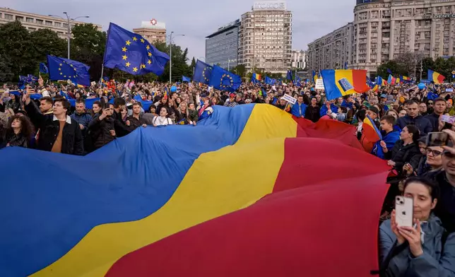 People wave Romanian and EU flags during a Pro-EU rally ahead of the second round of the presidential election redo in Bucharest, Romania, Friday, May 9, 2025. (AP Photo/Andreea Alexandru)