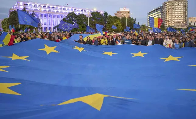 People hold an European Union flag during a pro-EU rally ahead of the second round of the presidential election redo in Bucharest, Romania, Friday, May 9, 2025. (AP Photo/Vadim Ghirda)