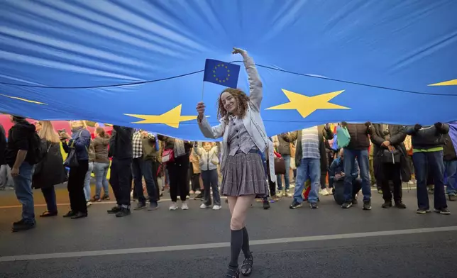 Corina Chirila stands under an European Union flag during a pro-EU rally ahead of the second round of the presidential election redo in Bucharest, Romania, Friday, May 9, 2025. (AP Photo/Vadim Ghirda)