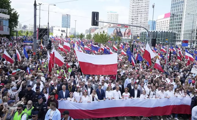 The liberal presidential candidate Rafal Trzaskowski holds a giant polish flag in the first row as he stands next to a waving women during a march one week ahead of a decisive presidential election in Warsaw, Poland on Sunday, May 25, 2025. (AP Photo/Czarek Sokolowski)