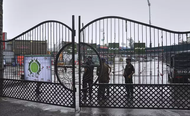 Police officers stand guard behind a closed gate of an entry point to Pindi Cricket Stadium following a suspected Indian drones crashed in the parking area, in Rawalpindi, Pakistan, Thursday, May 8, 2025. (AP Photo/W.K. Youszai)