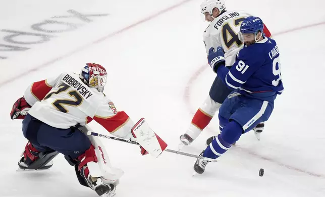 Florida Panthers goaltender Sergei Bobrovsky (72) pokes the puck away from Toronto Maple Leafs' John Tavares (91) as he tries to move past Panthers' Gustav Forsling (42) during first period NHL playoff hockey action in Toronto on Wednesday, May 14, 2025. (Frank Gunn/The Canadian Press via AP)