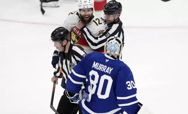 Florida Panthers' Jonah Gadjovich (12) is held back by linesman Kiel Murchison (79) as he goes after Toronto Maple Leafs goaltender Matt Murray (30) during third period NHL playoff hockey action in Toronto on Wednesday, May 14, 2025. (Frank Gunn/The Canadian Press via AP)