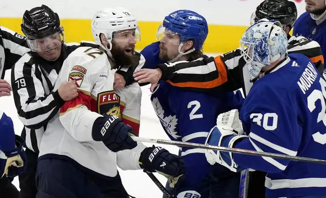 Florida Panthers' Jonah Gadjovich (12) is held back by linesman Kiel Murchison (79) as he goes after Toronto Maple Leafs goaltender Matt Murray (30) during third period NHL playoff hockey action in Toronto on Wednesday, May 14, 2025. (Frank Gunn/The Canadian Press via AP)
