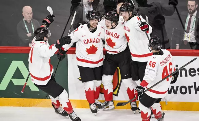 Canada's Macklin Celebrini, center, celebrates scoring with teammates during the IIHF Ice Hockey World Championship group A match between Sweden and Canada in Stockholm, Sweden, Tuesday, May 20, 2025. (Fredrik Sandberg/TT News Agency via AP)