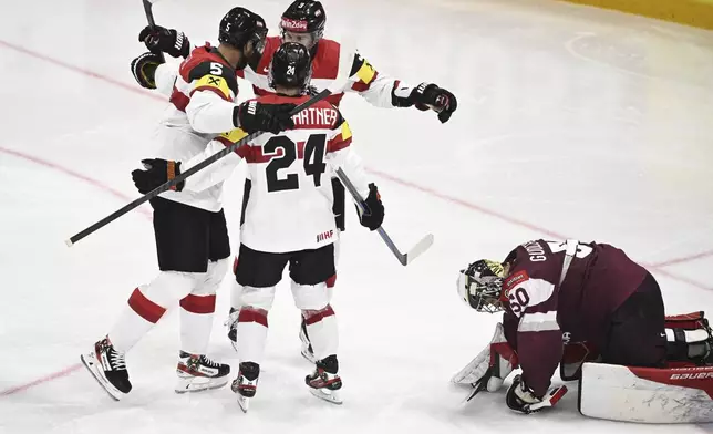 Austria's Thomas Raffl, left, celebrates after scoring his side's fourth goal during the IIHF Ice Hockey World Championship group A match between Latvia and Austria in Stockholm, Sweden, Tuesday, May 20, 2025. (Pontus Lundahl/TT News Agency via AP)