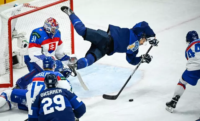 Finland's Jesper Mattila, center, in action in front of Slovakia goalkeeper Samuel Hlavaj, left, and Mislav Rosandic, right, during the IIHF Ice Hockey World Championship group A match between Slovakia and Finland in Stockholm, Sweden, Tuesday, May 20, 2025. (Fredrik Sandberg/TT News Agency via AP)