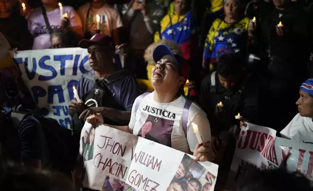 People with photos of their relatives who were deported from the U.S. to a prison in El Salvador, for being alleged members of the Tren de Aragua gang, cry and pray outside El Salvador's embassy in Caracas, Venezuela, April 2, 2025. (AP Photo/Ariana Cubillos)