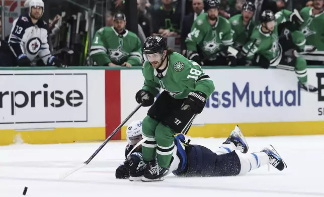 Dallas Stars' Sam Steel (18) is tripped by Winnipeg Jets' Mark Scheifele as Steel chases after the puck in the third period of Game 6 of a second-round NHL hockey playoff series in Dallas, Saturday, May 17, 2025. (AP Photo/Gareth Patterson)