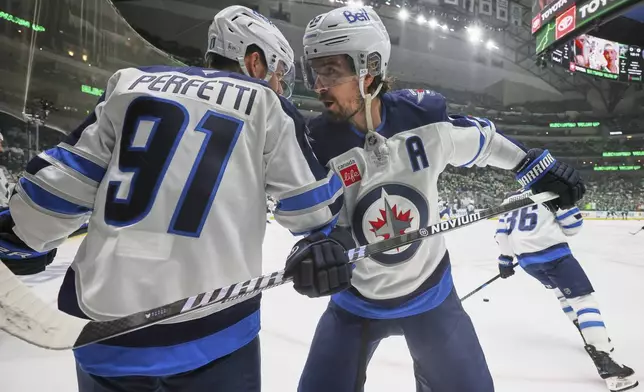 Winnipeg Jets' Cole Perfetti (91) and Mark Scheifele, right, talk during warmups before first Game 6 of a second-round NHL hockey playoff series against the Dallas Stars in Dallas, Saturday, May 17, 2025. (AP Photo/Gareth Patterson)