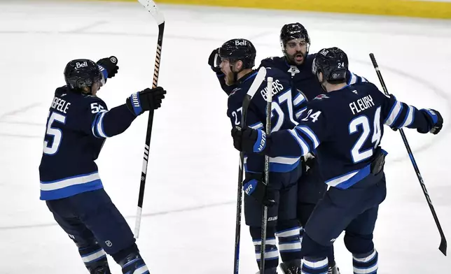 Winnipeg Jets' Nikolaj Ehlers (27) celebrates after his goal against the Dallas Stars with Mark Scheifele (55), Haydn Fleury (24) and Dylan Demelo (2) during the first period of Game 2 of a second-round NHL hockey playoff series in Winnipeg, Manitoba, Friday, May 9, 2025. (Fred Greenslade/The Canadian Press via AP)