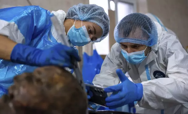 Forensic workers at a morgue in Kyiv, Ukraine, examine the body of a Ukrainian prisoner of war returned by Russia, June 24, 2024. (AP Photo/Alex Babenko)
