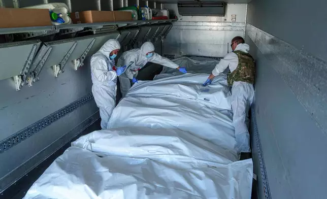 FILE - International Committee of the Red Cross workers in the Sumy region of Ukraine inspect body bags holding Russian soldiers, May 31, 2024. (AP Photo/Evgeniy Maloletka, File)