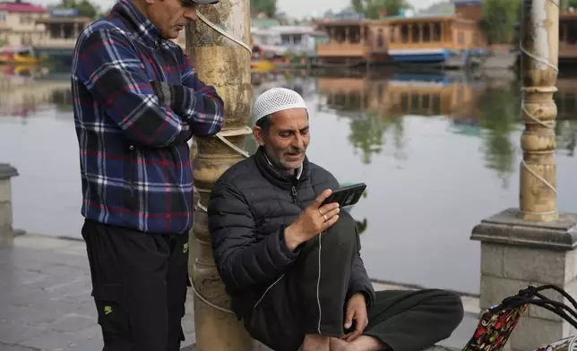 Kashmiri men watch news on a cell phone at Dal lake in Srinagar, Indian controlled Kashmir, Wednesday, May 7, 2025. (AP Photo/Mukhtar Khan)