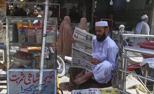 A Pakistani man reads morning news paper with front page story about Pakistan and India military tension, at a market in Peshawar, Pakistan, Friday, May 9, 2025. (AP Photo/Muhammad Sajjad)