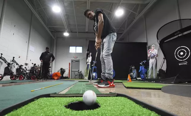 Jacento White, 16, a junior golfer at Renaissance High School practices putting in Detroit, Thursday, Feb. 27, 2025. (AP Photo/Paul Sancya)