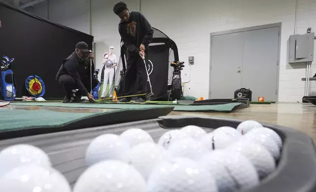 Shaun Horne, 16, a junior at Renaissance High School works on putting with golf coach Jess Hawkins in Detroit, Thursday, Feb. 27, 2025. (AP Photo/Paul Sancya)