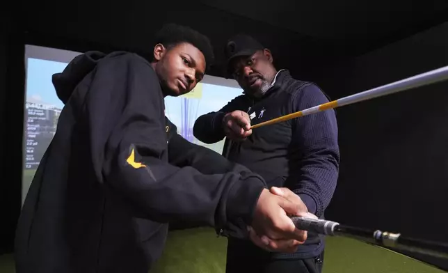 Shaun Horne, 16, a junior at Renaissance High School works on his swing with golf coach Jess Hawkins in Detroit, Thursday, Feb. 27, 2025. (AP Photo/Paul Sancya)