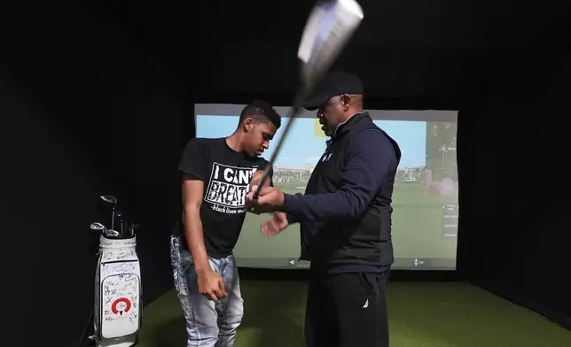 Jacento White, 16, a junior at Renaissance High School works on his swing with golf coach Jess Hawkins in Detroit, Thursday, Feb. 27, 2025. (AP Photo/Paul Sancya)