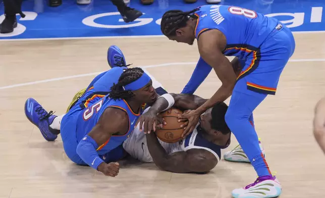 Minnesota Timberwolves forward Julius Randle, center, fights for the ball against Oklahoma City Thunder guard Luguentz Dort, left, and forward Jalen Williams during the first half of Game 2 of an NBA basketball Western Conference Finals playoff series Thursday, May 22, 2025, in Oklahoma City. (AP Photo/Nate Billings)