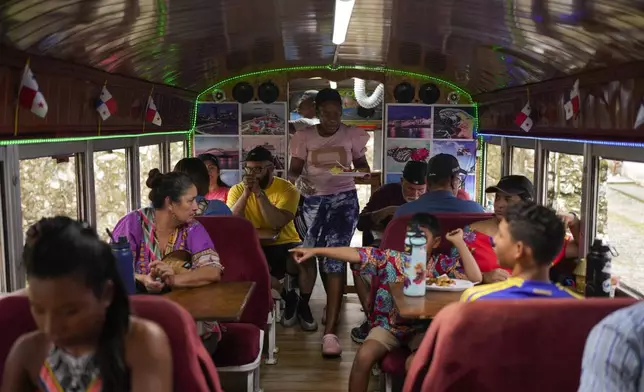 A waitress serves patrons inside a Red Devil restaurant in Portobelo, Panama, Saturday, May 3, 2025. The Red Devils are former U.S. school buses once used in the Panama Canal Zone and later as public transport, now adapted for private and cultural use. (AP Photo/Matias Delacroix)