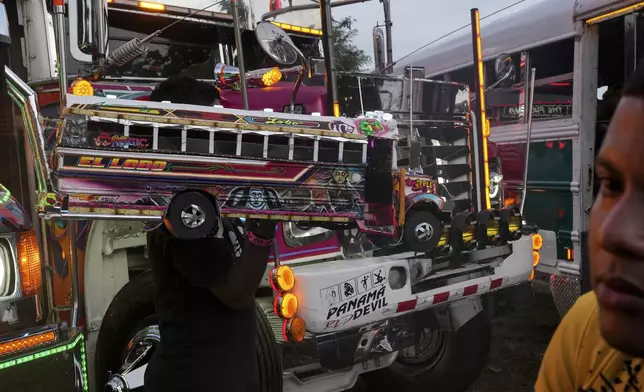A man carries a model of a bus known as a Red Devil during a show in La Chorrera, Panama, Sunday, June 30, 2024. The Red Devils are former U.S. school buses once used in the Panama Canal Zone and later as public transport, now repurposed for private and cultural use. (AP Photo/Matias Delacroix)