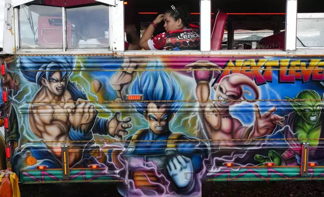 A woman sits inside a bus during a Red Devils exhibition show in Chilibre, Panama, Sunday, May 4, 2025. The Red Devils are former U.S. school buses once used in the Panama Canal Zone and later as public transport or adapted for private and cultural use. (AP Photo/Matias Delacroix)