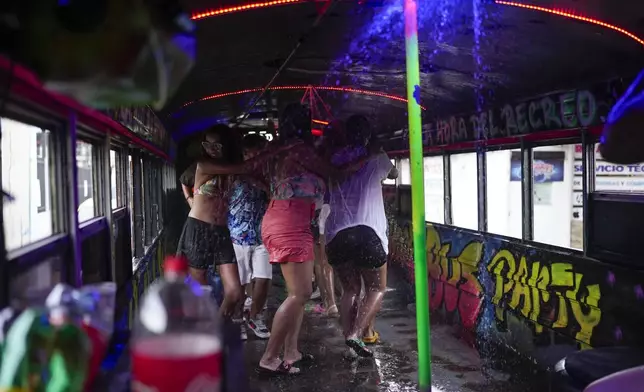 People dance inside a Red Devil party bus in Panama City, Sunday, Aug. 25, 2024. The Red Devils are former U.S. school buses once used in the Panama Canal Zone and later as public transport, now repurposed for private and cultural use. (AP Photo/Matias Delacroix)