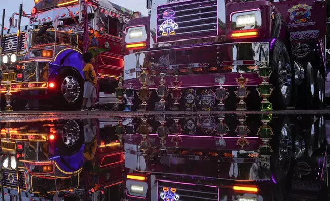 A boy watches buses during a Red Devils tuning exhibition in La Chorrera, Panama, Sunday, June 30, 2024. The Red Devils are repurposed U.S. school buses once used in the Panama Canal Zone and later as public transport, now adapted for private and cultural use. (AP Photo/Matias Delacroix)