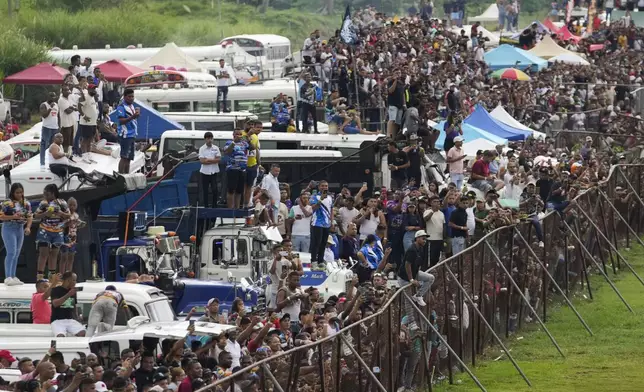 Spectators watch Red Devil buses race at a track in La Chorrera, Panama, Sunday, May 18, 2025. Red Devils are former U.S. school buses once used in the Panama Canal Zone, later repurposed as public transport or adapted for private and cultural use. (AP Photo/Matias Delacroix)