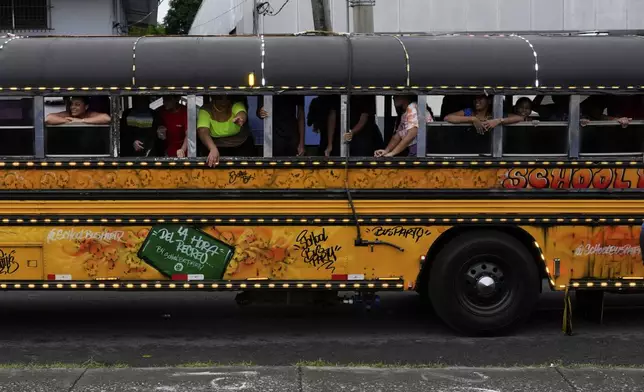 Party goers ride on a Red Devil party bus in Panama City, Sunday, Aug. 25, 2024. The The Red Devils are repurposed U.S. school buses once used in the Panama Canal Zone and later as public transport or adapted for private and cultural use. (AP Photo/Matias Delacroix)