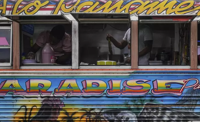 A cook fries fish inside a Red Devil restaurant bus in Portobelo, Panama, Saturday, May 3, 2025.The Red Devils are repurposed U.S. school buses once used in the Panama Canal Zone and later as public transport or adapted for private and cultural use. (AP Photo/Matias Delacroix)