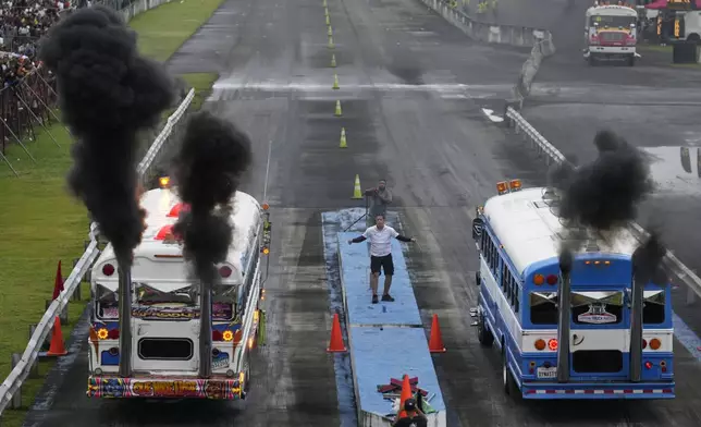 Red Devil buses race at a track in La Chorrera, Panama, Sunday, May 18, 2025. Red Devils are U.S. school buses once used in the Panama Canal Zone, later repurposed as public transport or adapted for private and cultural uses. (AP Photo/Matias Delacroix)