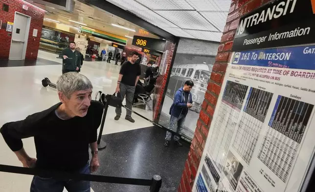 A commuter checks a NJ Transit bus schedule in the Port Authority Bus Terminal, in New York, Friday, May 16, 2025. (AP Photo/Richard Drew)