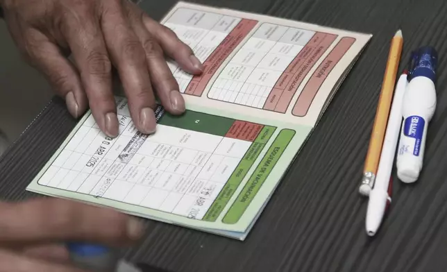 A health worker stamps a vaccination card at the health center where measles vaccinations are given in Ciudad Juarez, Chihuahua state, Mexico, Wednesday, April 30, 2025. (AP Photo/Christian Chavez)