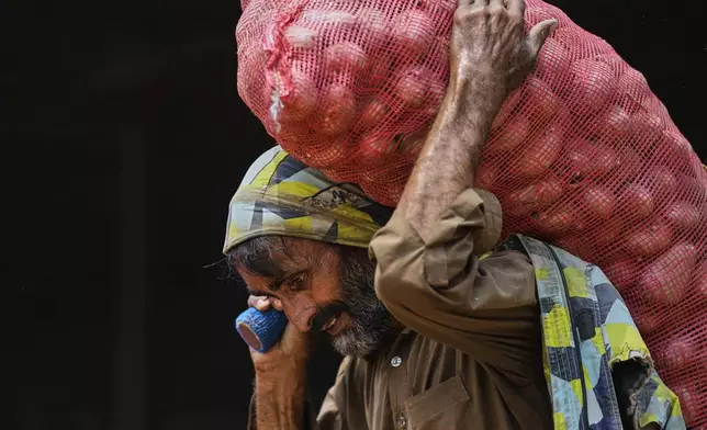 A laborer carries a sack of potatoes to load it into a mini truck at a wholesale vegetable market, during May Day in Islamabad, Pakistan, Thursday, May 1, 2025. (AP Photo/Anjum Naveed)
