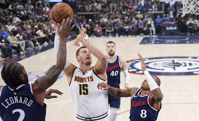 Denver Nuggets center Nikola Jokic, second from left, shoots as Los Angeles Clippers forward Kawhi Leonard, left, and guard Kris Dunn defend during the first half in Game 6 of an NBA basketball first-round playoff series Thursday, May 1, 2025, in Inglewood, Calif. (AP Photo/Mark J. Terrill)