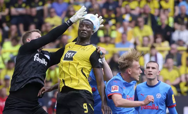 Dortmund's Serhou Guirassy, center, and Kiel goalkeeper Thomas Dahne in action during the German Bundesliga soccer match between Borussia Dortmund and Holstein Kiel at Signal Iduna Park in Dortmund, Germany, Saturday, May 17, 2025. (Bernd Thissen/dpa via AP)