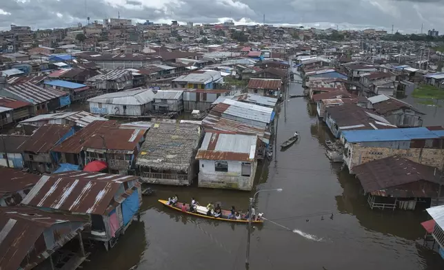 Relatives and friends ride with the coffin of Jorge Luis Mendoza Cuelho, 14, who died electrocuted in the river, during his funeral in Belen, a district nicknamed "Venice of the Jungle" in Iquitos, Peru, Friday, May 23, 2025. (AP Photo/Rodrigo Abd)