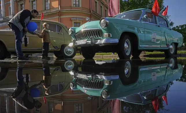 A man and a child examine a Soviet era GAZ M21 Volga car at a transport festival in St. Petersburg, Russia, Saturday, May 24, 2025. (AP Photo/Dmitri Lovetsky)