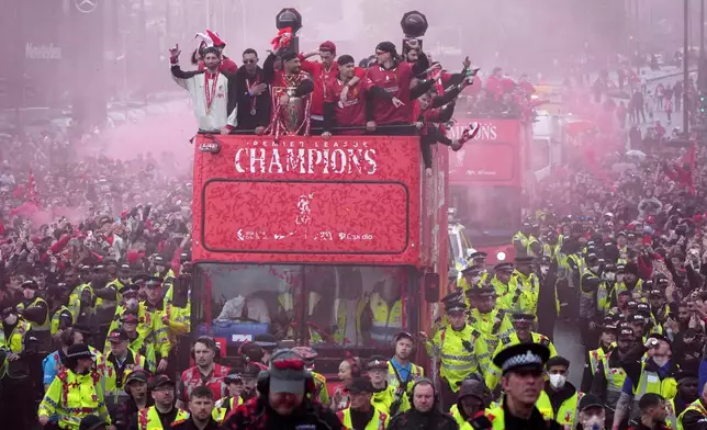 Liverpool players celebrate with the trophy on an open-top bus during the Liverpool FC Premier League victory parade in Liverpool, England, Monday, May 26, 2025. (AP Photo/Jon Super)