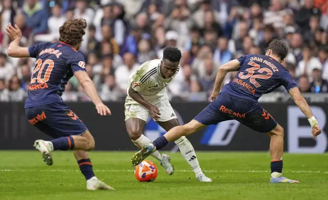 Real Madrid's Vinicius Junior, centre, challenges for the ball with Celta's Marcos Alonso, left, and Celta's Javi Rodriguez during the Spanish La Liga soccer match between Real Madrid and Celta Vigo at the Santiago Bernabeu stadium in Madrid, Spain, Sunday, May 4, 2025. (AP Photo/Jose Breton)