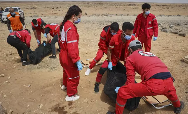 Syrian Red Crescent workers collect bodies off a highway of a convoy of Syrian Druze fighters who were heading from the southern Sweida province towards the capital to support their people, at al-Sor al-Kobra village near the Sweida town, southern Syria, Thursday, May 1, 2025. (AP Photo/Omar Albam)